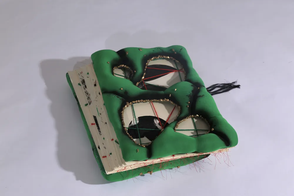 The artbook closed: a green padded cover with stitched openings