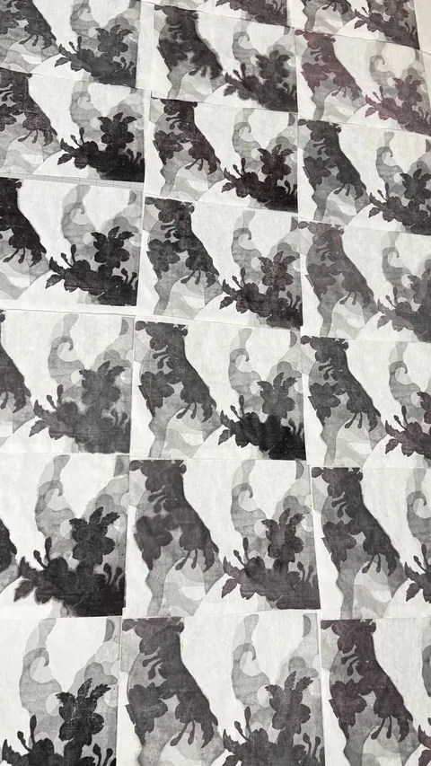 A grid of printed sheets: repeated black blossom shapes over grey washes
