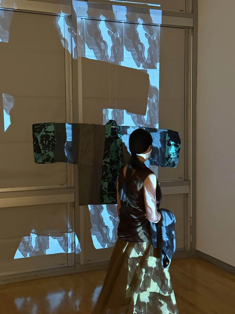 A figure wearing the printed paper garment, lit by the projected stop-motion film