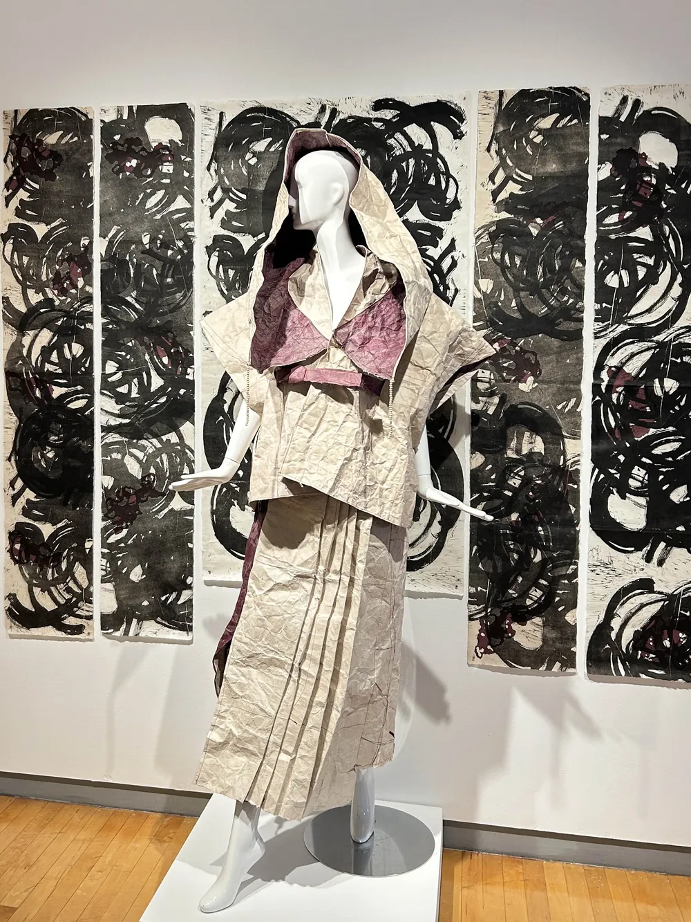 A paper garment on a mannequin before large ink prints