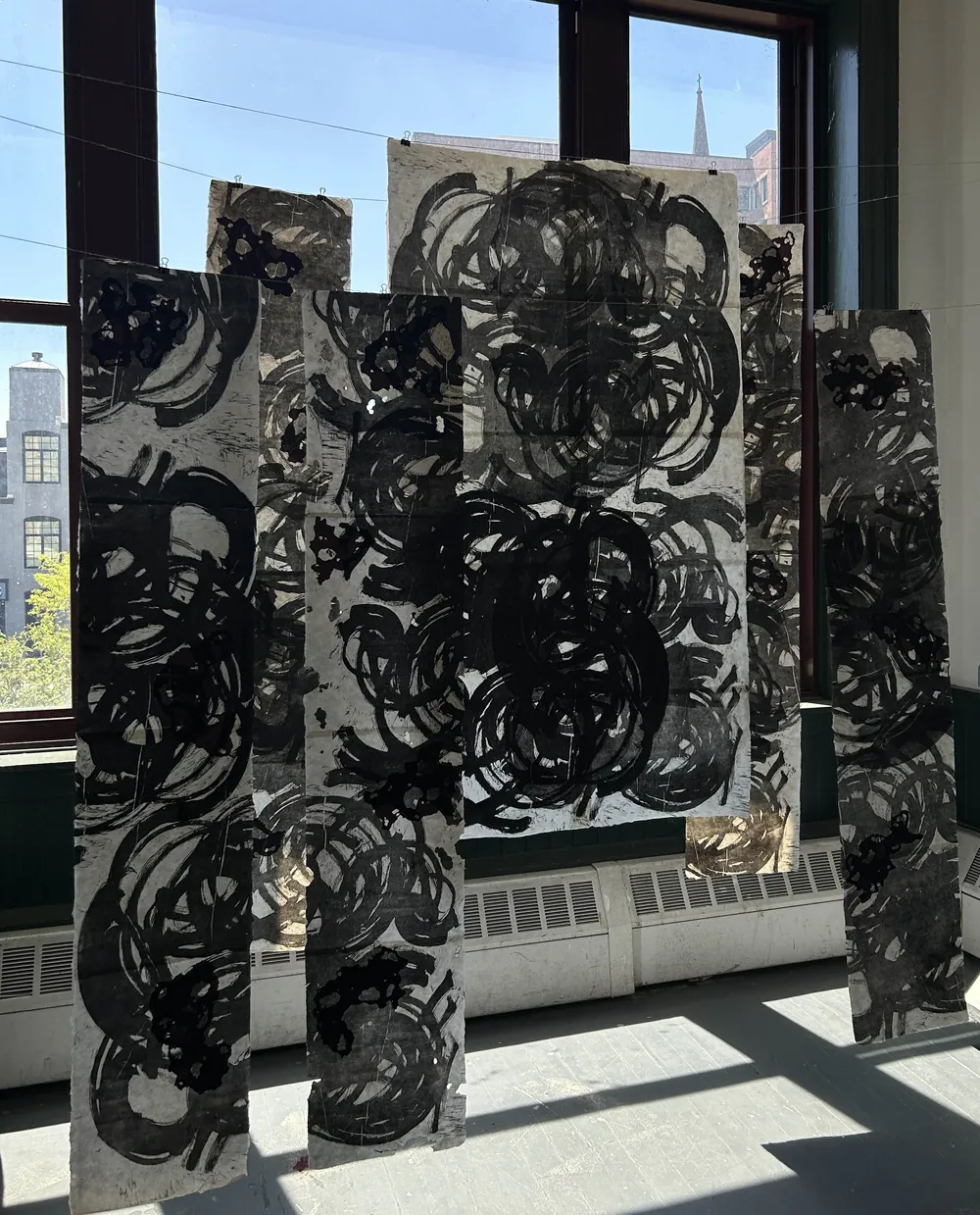 Woodcut-printed stone panels standing in a sunlit window